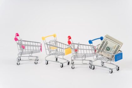 Miniature shopping carts in bright colors with dollar bills imply financial shopping themes.