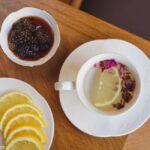 Elegant setup of lemon tea alongside fig jam and lemon slices on a wooden table.