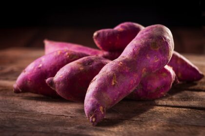 Close-up of purple sweet potatoes on a wooden surface, perfect for culinary and natural food themes.