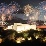 Fogos de artifício iluminando o Forte São Mateus em Cabo Frio durante o Réveillon 2026, com o mar e o pôr do sol ao fundo.