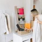 A woman in casual attire unpacking a delivery box with clothing at home, engaging in online shopping.