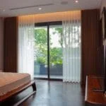 Interior of a peaceful bedroom featuring a bed and balcony views of lush greenery.