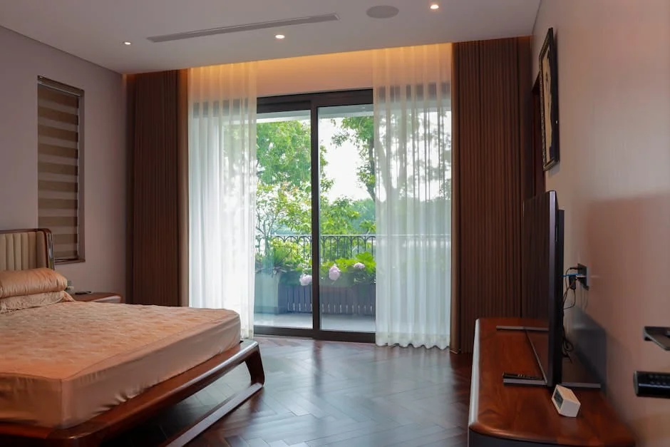Interior of a peaceful bedroom featuring a bed and balcony views of lush greenery.