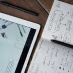Digital and handwritten brainstorming tools on a wooden desk, ideal for business and study contexts.