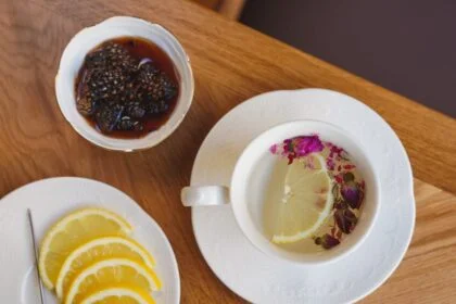 Elegant setup of lemon tea alongside fig jam and lemon slices on a wooden table.