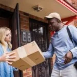 A delivery man handing a package to a woman at her doorstep, emphasizing delivery services.