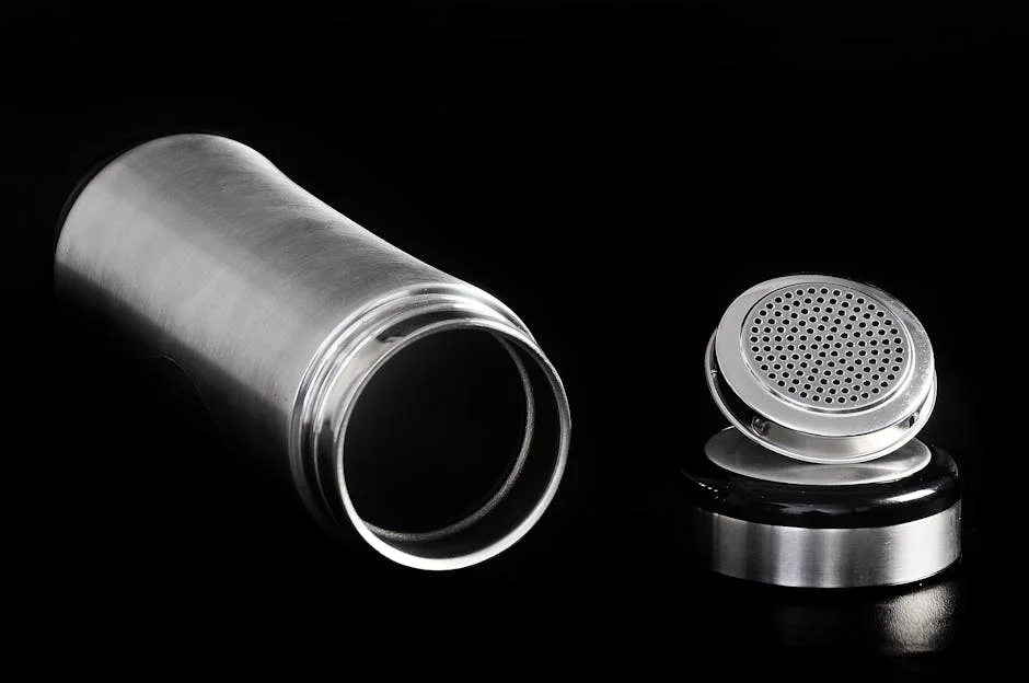 A sleek stainless steel thermos flask and cap displayed on a black backdrop, highlighting modern design.