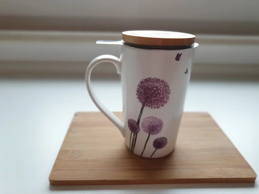 Elegant ceramic cup with lid, featuring purple floral design, on a wooden board.