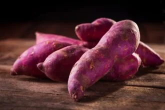 Close-up of purple sweet potatoes on a wooden surface, perfect for culinary and natural food themes.