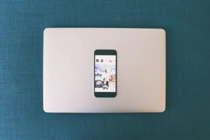 Flat lay of a smartphone on a laptop with social media photos on screen.